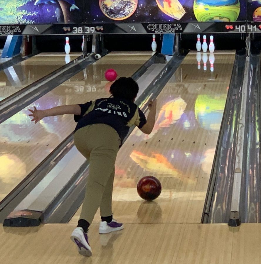A student bowls to hit the last three pins.