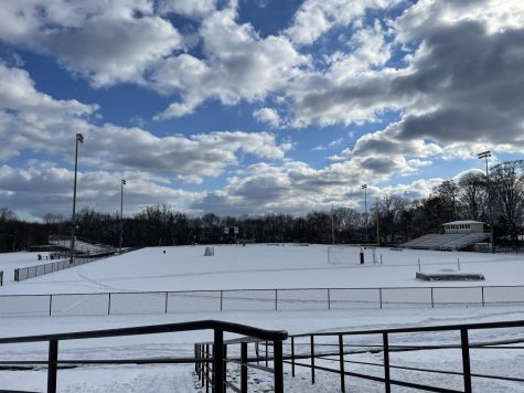 The snow covers the football field at the school. 