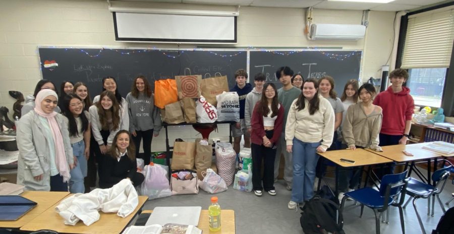 Social studies teacher Jennifer Fernandez and her history students pose in front of donations.