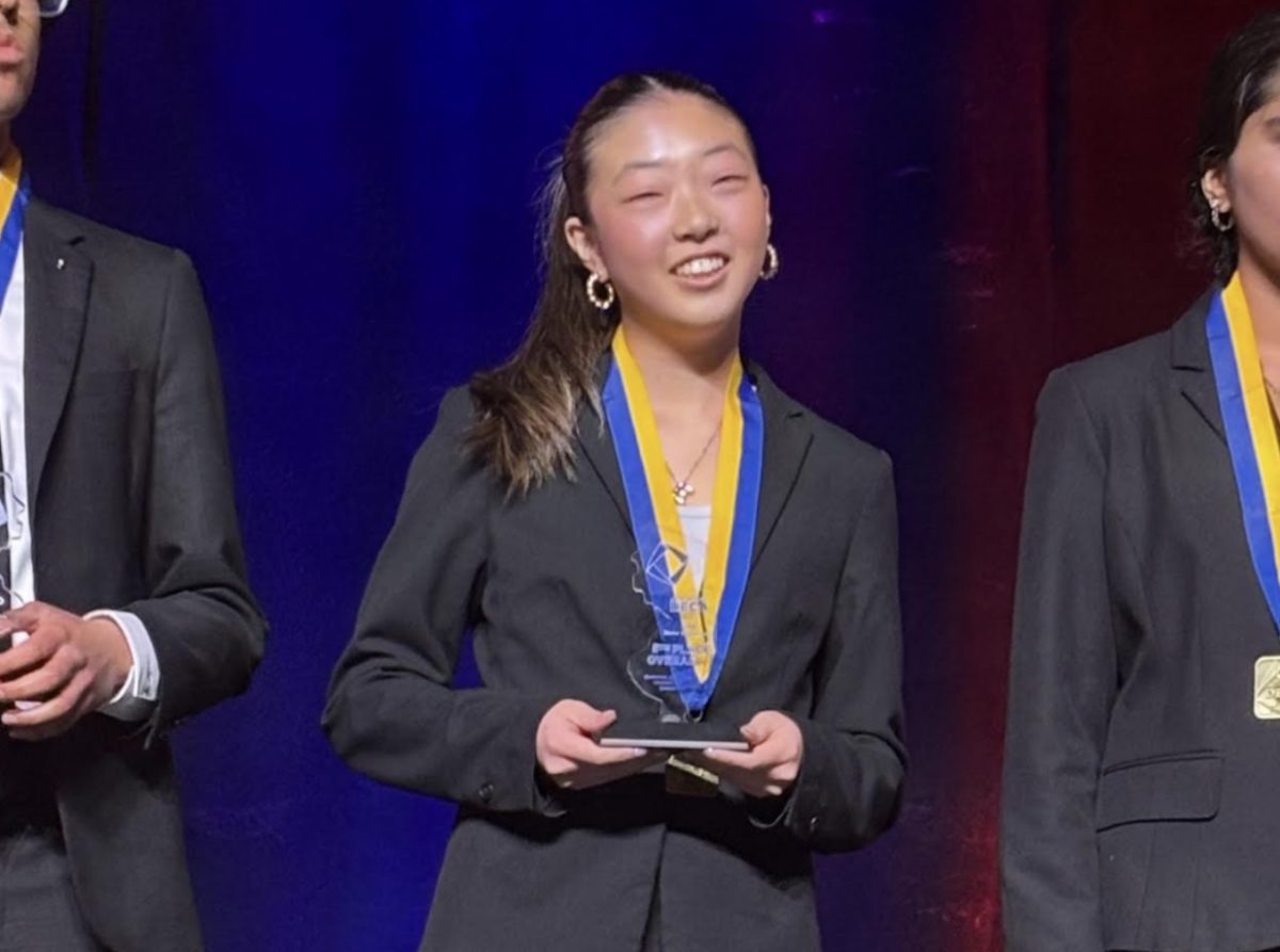 Ellie Kim on the DECA ICDC stage, receiving her plaque as a Top Ten National finalist 
