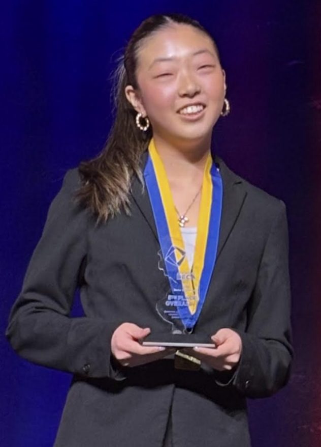 Ellie Kim on the DECA ICDC stage, receiving her plaque as a Top Ten National finalist 