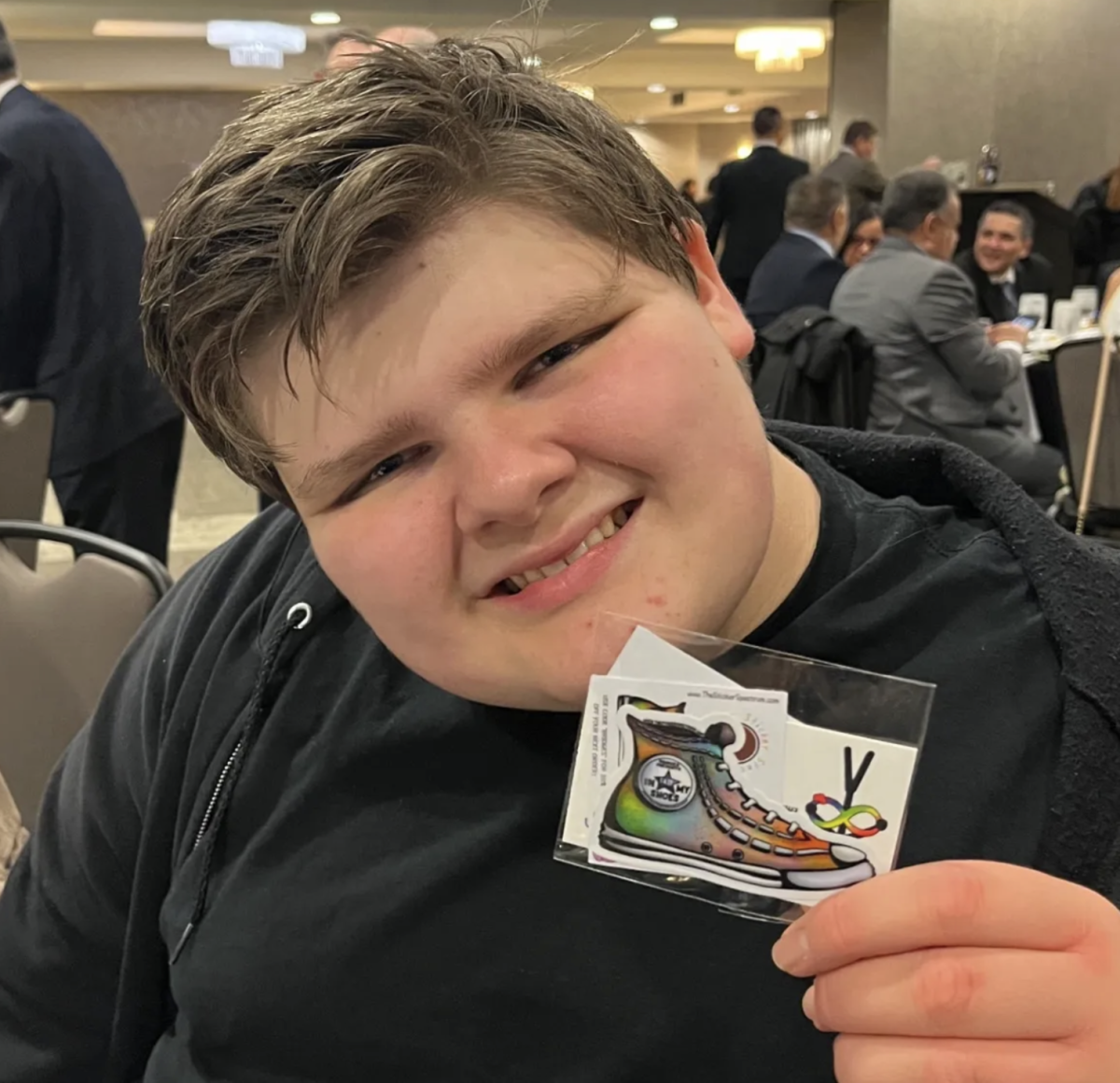 Liam McCormack holding a pack of stickers designed by him, available on The Sticker Spectrum.